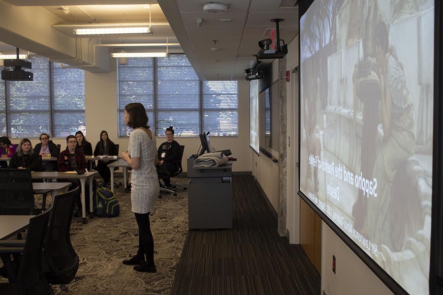 Professor teaches mock class to room of students.