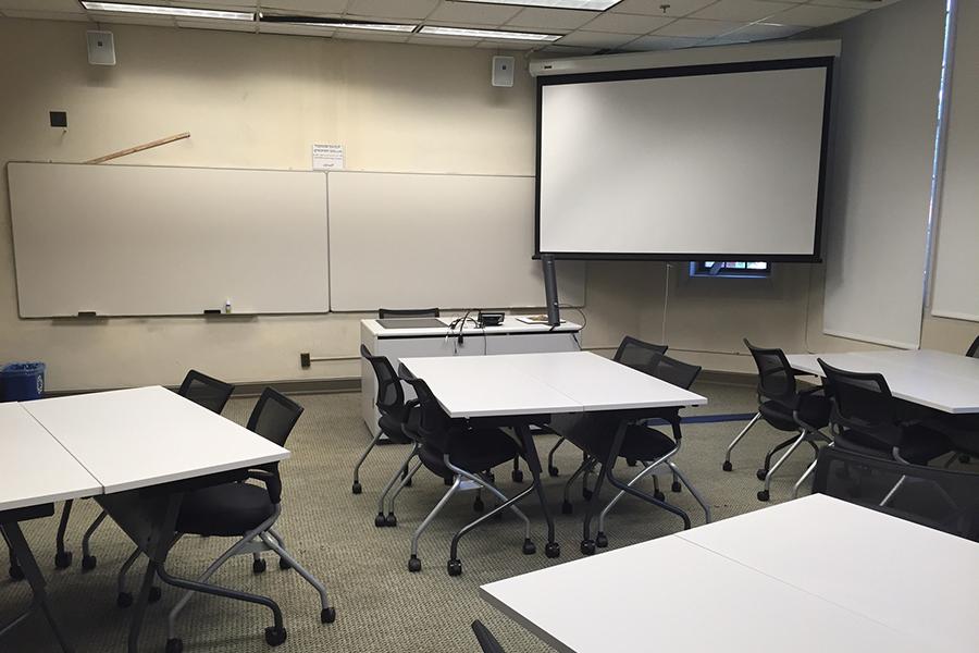 Buttrick classroom with desks, projection screen and whiteboards